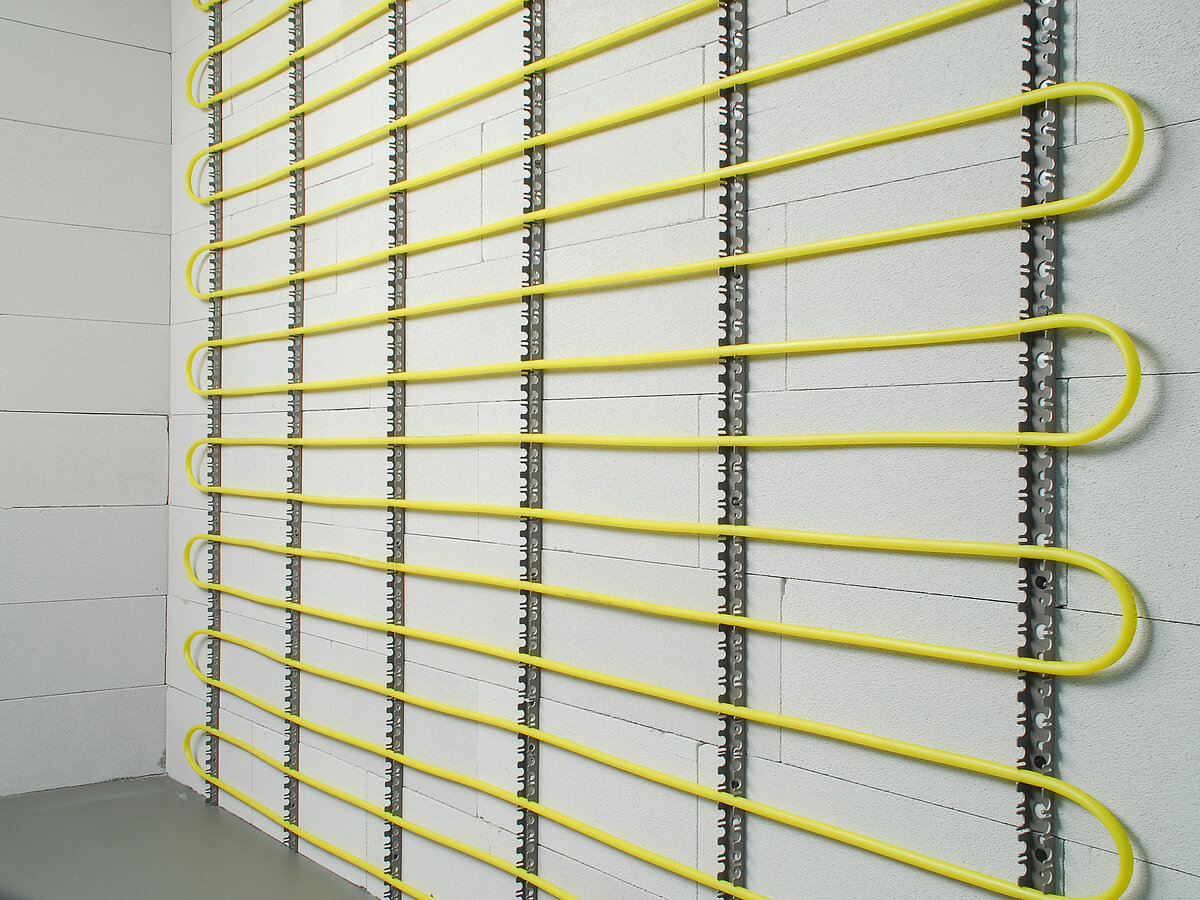 Eigenstabile Befestigung und Positionierung der Systemrohre einer Flächenheizung/-kühlung an Wänden und Decken mit Befestigungsschienen